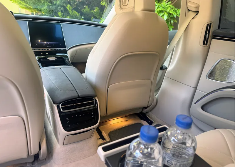 Ásványvíz a Mercedes-Benz EQS csendes hátsó utasterében vidéki transzfer közben